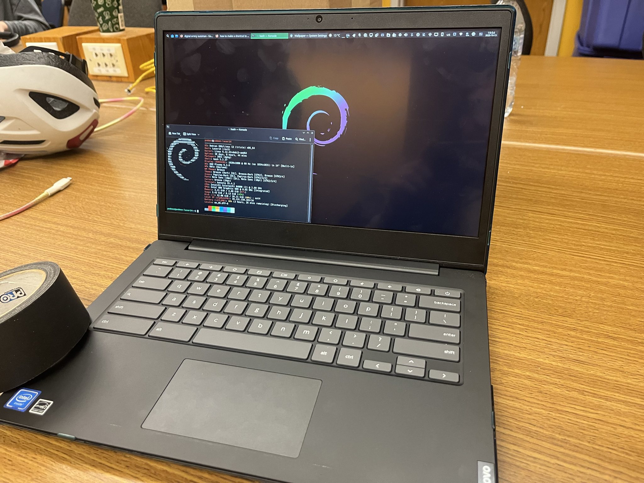 A laptop running Debian with Fastfetch in the terminal.